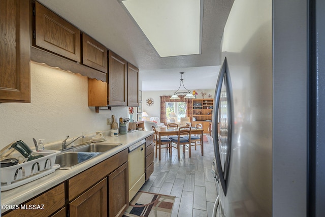 kitchen with pendant lighting, sink, stainless steel refrigerator, and dishwasher