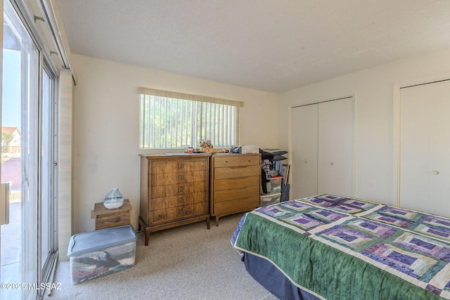 bedroom with carpet floors, two closets, and a textured ceiling