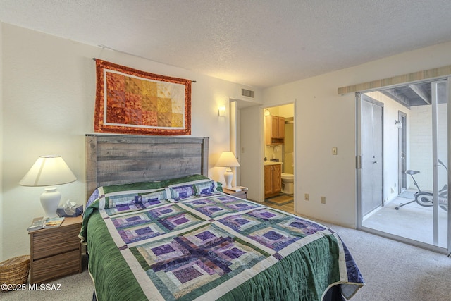 bedroom featuring ensuite bathroom, carpet flooring, a textured ceiling, and access to outside