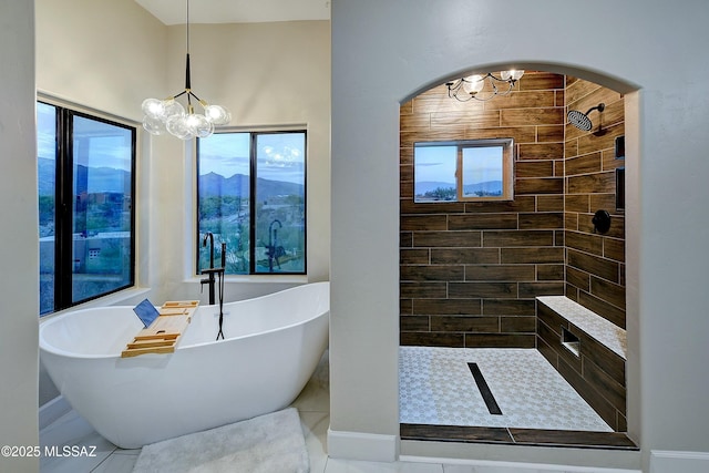 bathroom with a soaking tub, a notable chandelier, and a tile shower