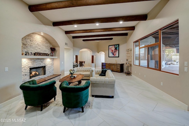 living room featuring arched walkways, a fireplace, visible vents, and baseboards