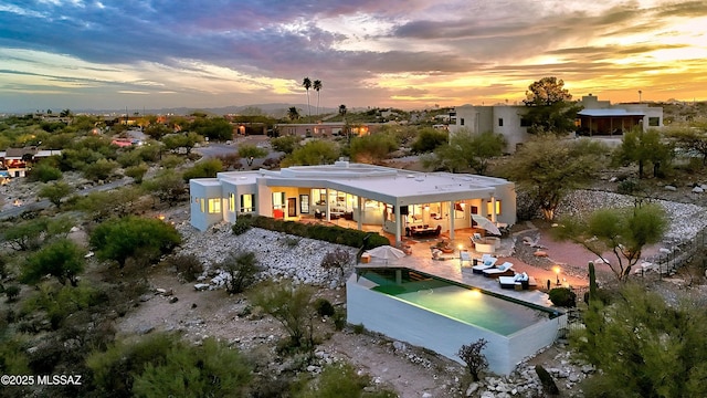 rear view of property featuring a pool and a patio