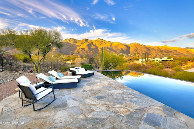 exterior space with outdoor lounge area, a mountain view, and fence