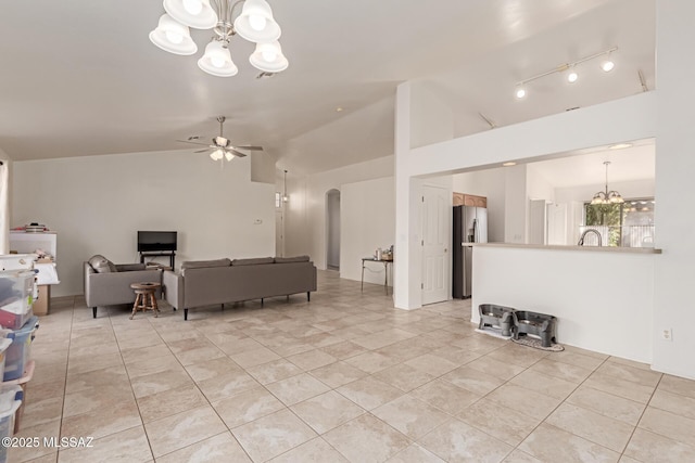 living room with lofted ceiling, light tile patterned floors, ceiling fan with notable chandelier, and sink