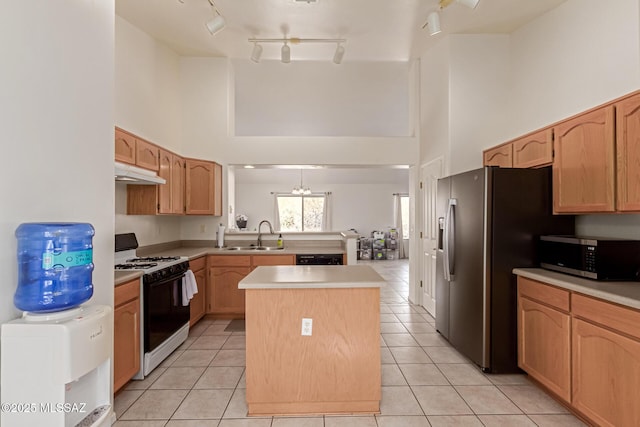 kitchen with sink, light tile patterned floors, appliances with stainless steel finishes, a high ceiling, and a kitchen island