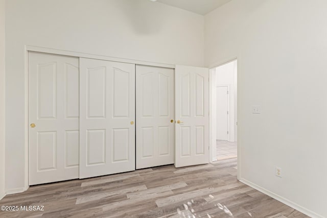 unfurnished bedroom featuring a closet, light hardwood / wood-style flooring, and a high ceiling