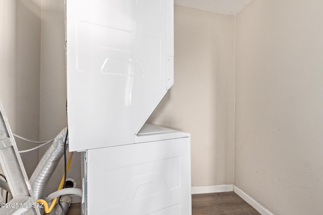 clothes washing area with dark wood-type flooring and stacked washer / dryer