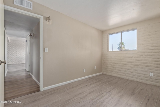 unfurnished room featuring brick wall