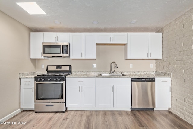 kitchen featuring white cabinetry, appliances with stainless steel finishes, sink, and light hardwood / wood-style flooring