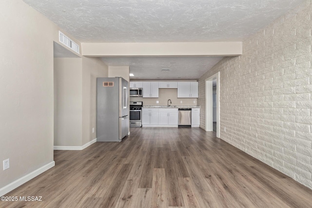 unfurnished living room featuring sink, a textured ceiling, and dark hardwood / wood-style flooring