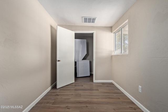 hallway featuring stacked washer / drying machine and dark hardwood / wood-style floors