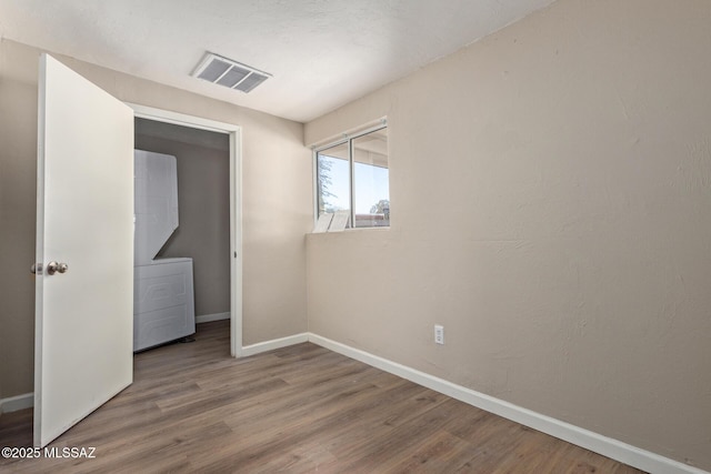 unfurnished bedroom featuring stacked washer / drying machine, hardwood / wood-style floors, and a closet