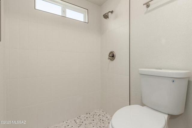 bathroom featuring tiled shower and toilet