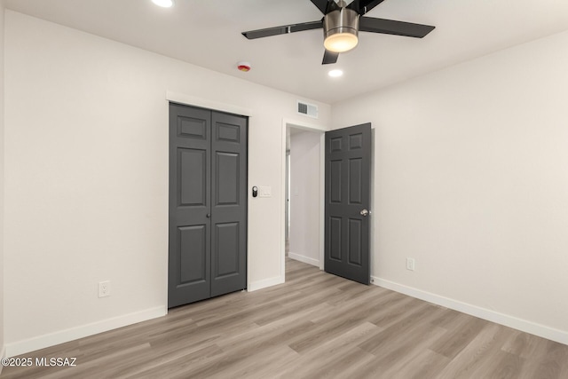 unfurnished bedroom with ceiling fan, a closet, and light wood-type flooring