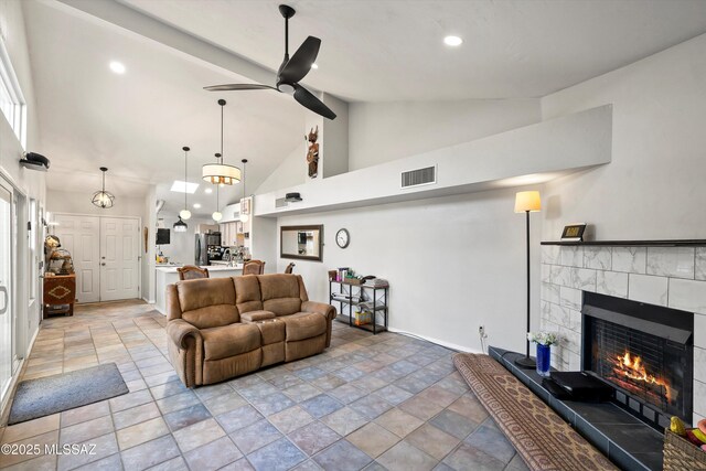 living room featuring vaulted ceiling, a tile fireplace, and ceiling fan