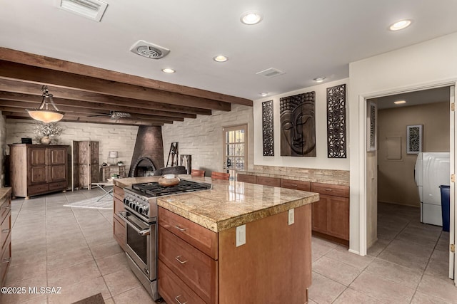 kitchen with decorative light fixtures, a center island, a wood stove, beam ceiling, and high end stove