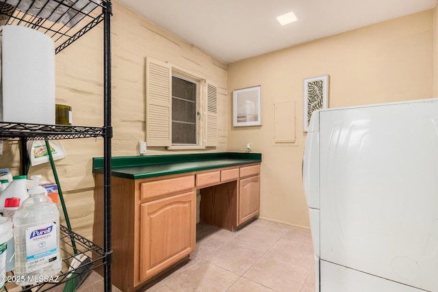 interior space with built in desk, washer / dryer, and light tile patterned floors