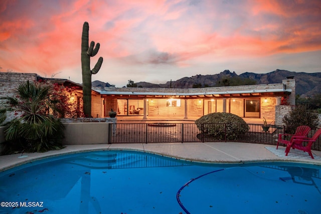 pool at dusk with a patio and a mountain view