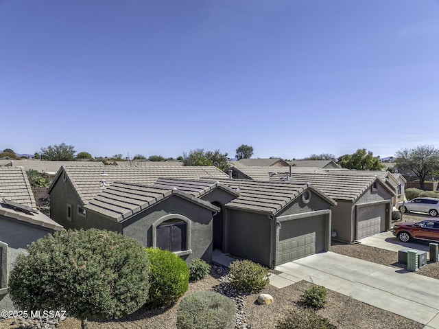 single story home featuring a tile roof, an attached garage, driveway, and stucco siding