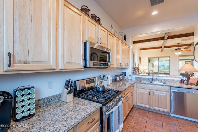 kitchen featuring sink, beam ceiling, stainless steel appliances, light stone countertops, and light brown cabinetry