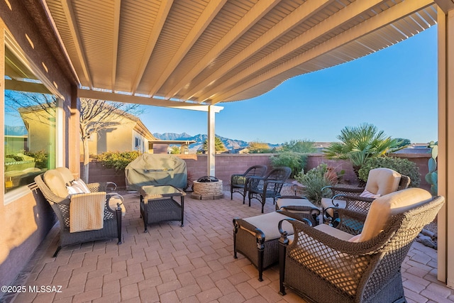 view of patio with a grill, a mountain view, and an outdoor living space with a fire pit