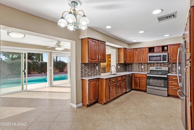 kitchen featuring light tile patterned flooring, sink, hanging light fixtures, appliances with stainless steel finishes, and backsplash