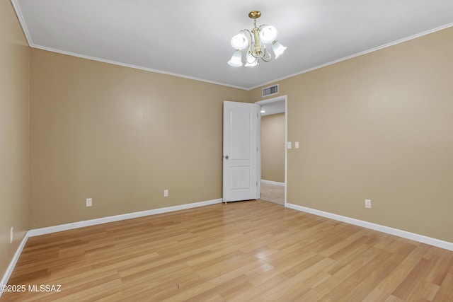 spare room featuring ornamental molding, light wood-type flooring, and a notable chandelier