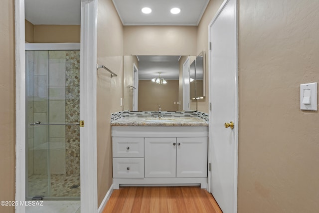 bathroom featuring vanity, wood-type flooring, a shower with door, and an inviting chandelier