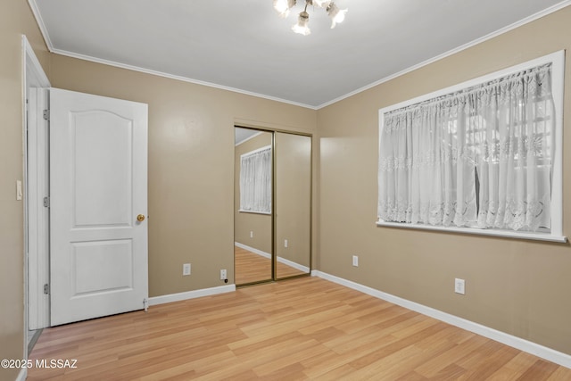 unfurnished bedroom featuring an inviting chandelier, crown molding, a closet, and light wood-type flooring