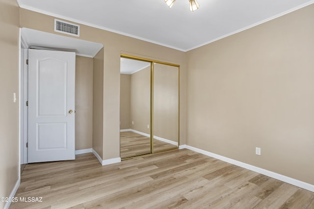 unfurnished bedroom with crown molding, light wood-type flooring, and a closet