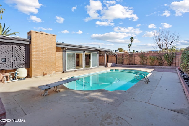 view of pool featuring a diving board and a patio