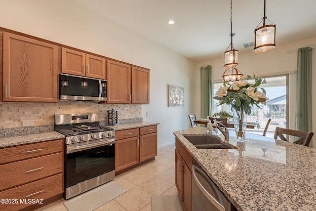 kitchen featuring sink, appliances with stainless steel finishes, light stone countertops, decorative backsplash, and decorative light fixtures