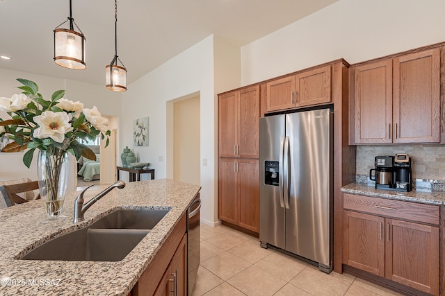 kitchen featuring pendant lighting, sink, decorative backsplash, light stone counters, and stainless steel appliances