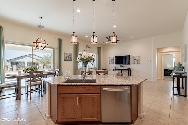 kitchen with pendant lighting, light tile patterned floors, light stone countertops, and a center island with sink