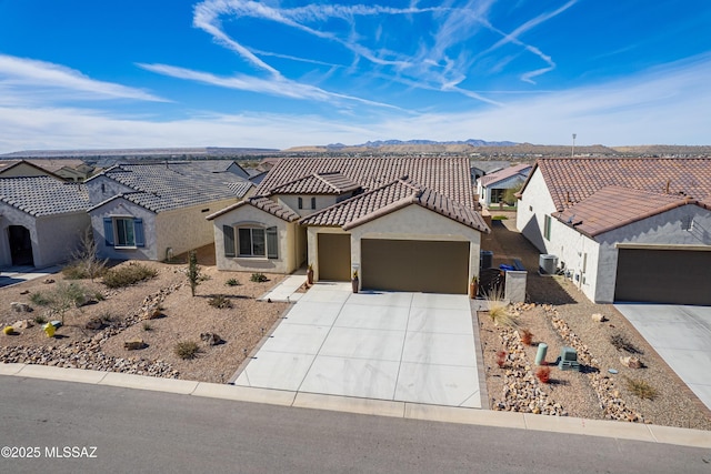 view of front of home featuring a garage, a mountain view, and central AC