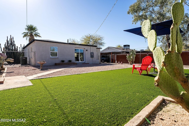 back of house with a yard, fence, cooling unit, and stucco siding