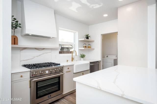 kitchen featuring washer / dryer, tasteful backsplash, appliances with stainless steel finishes, light stone counters, and open shelves