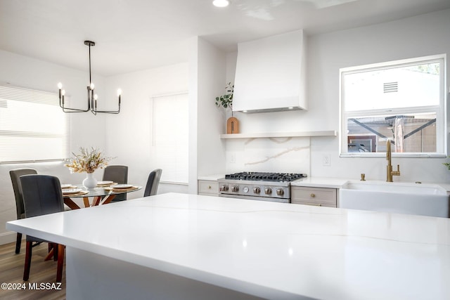 kitchen with range, light countertops, hanging light fixtures, and premium range hood