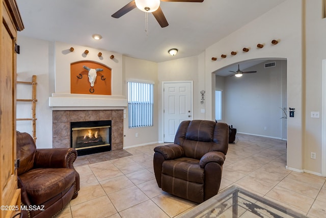 tiled living room featuring ceiling fan, lofted ceiling, and a fireplace