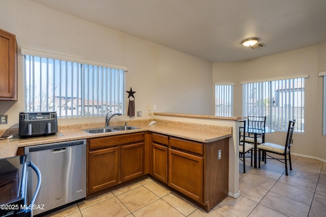 kitchen with sink, stainless steel dishwasher, light tile patterned floors, and kitchen peninsula