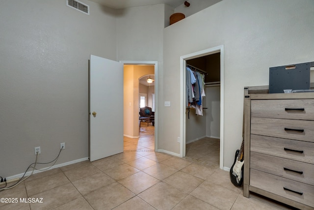 unfurnished bedroom with a towering ceiling, a spacious closet, a closet, and light tile patterned floors