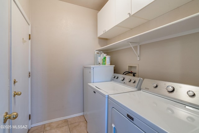 laundry area with cabinets, washer and dryer, and light tile patterned floors