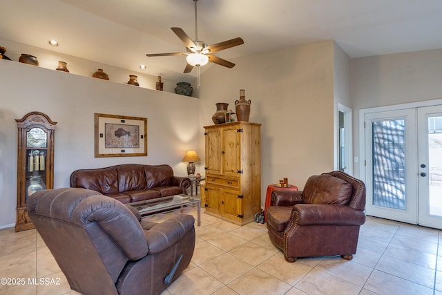 living room with a towering ceiling, light tile patterned floors, ceiling fan, and french doors