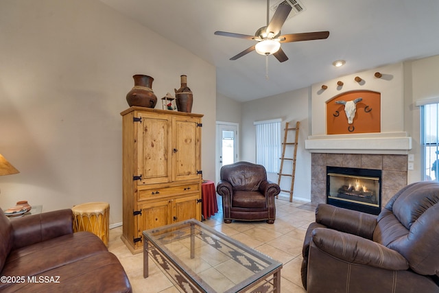 tiled living room featuring vaulted ceiling, ceiling fan, and a fireplace