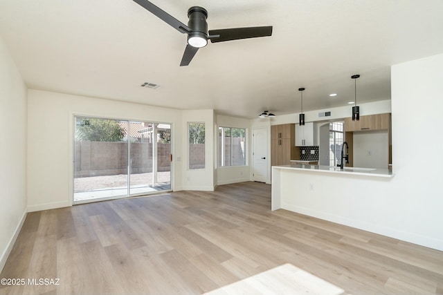 unfurnished living room featuring ceiling fan and light wood-type flooring