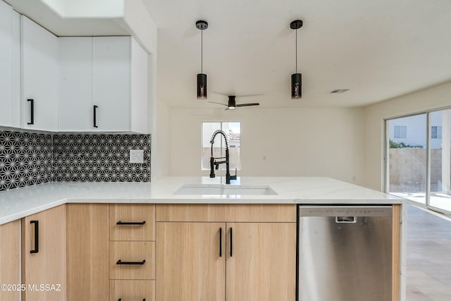 kitchen with sink, white cabinetry, light stone countertops, decorative light fixtures, and stainless steel dishwasher