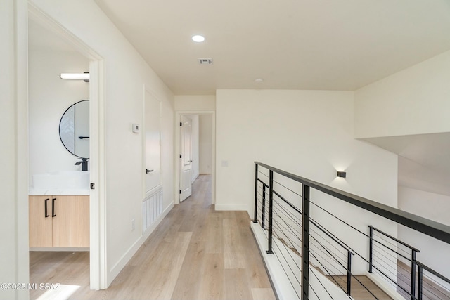 corridor featuring sink and light hardwood / wood-style flooring