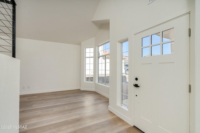 foyer entrance with high vaulted ceiling and light hardwood / wood-style floors