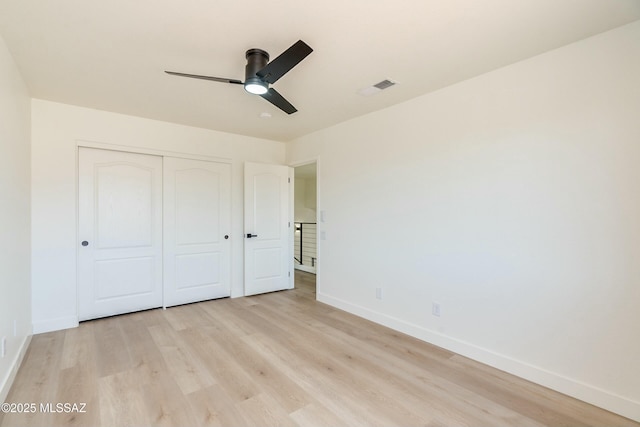 unfurnished bedroom featuring ceiling fan, light hardwood / wood-style floors, and a closet