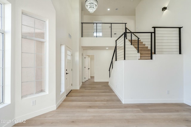 foyer with a notable chandelier, a towering ceiling, and light wood-type flooring